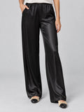 Front studio view of a model wearing Black satin wide leg pants with an elastic high waist and side pockets.