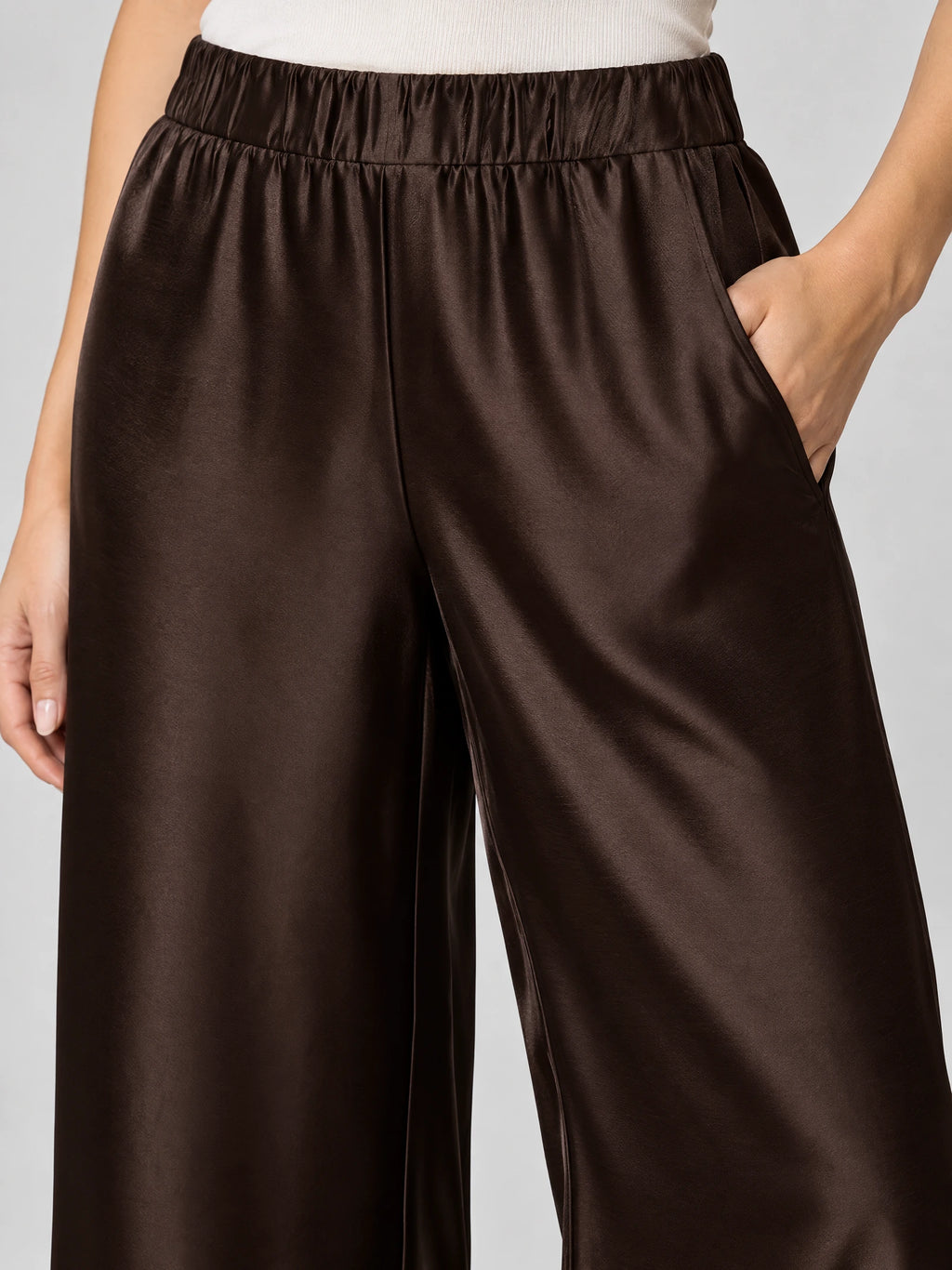 Close-up of Brown satin wide leg pants with a gathered high waistband and side pocket.