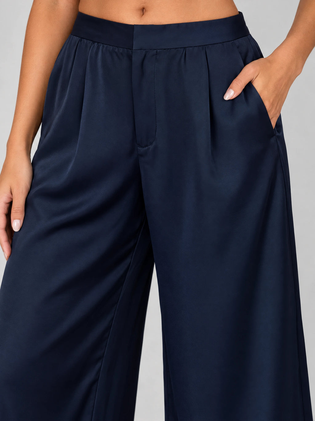 Close-up of Navy satin wide leg pants showing the high waistband, front pleats, and side pocket.