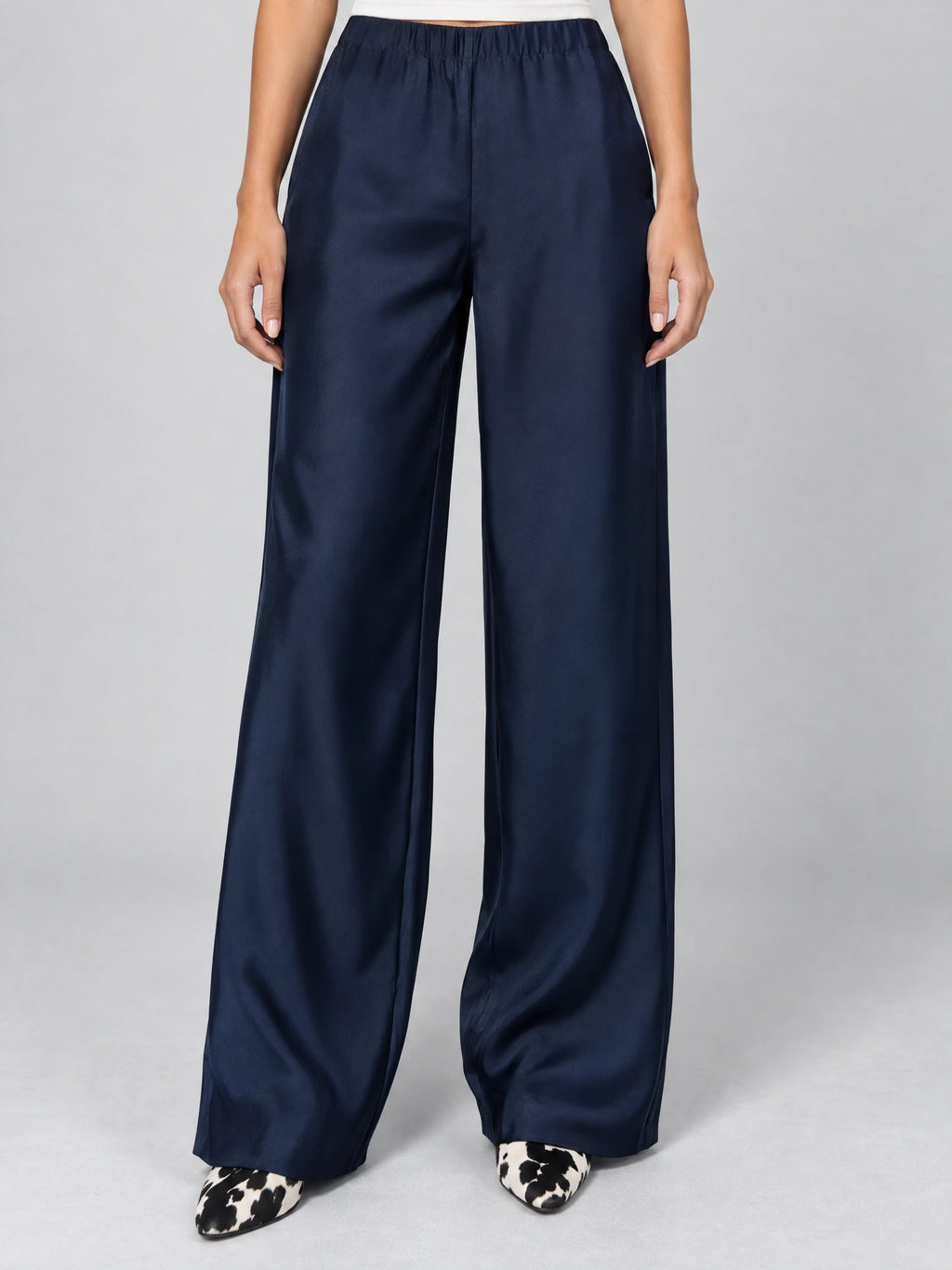 Front studio view of a model wearing Navy satin wide leg pants with a high elastic waist.