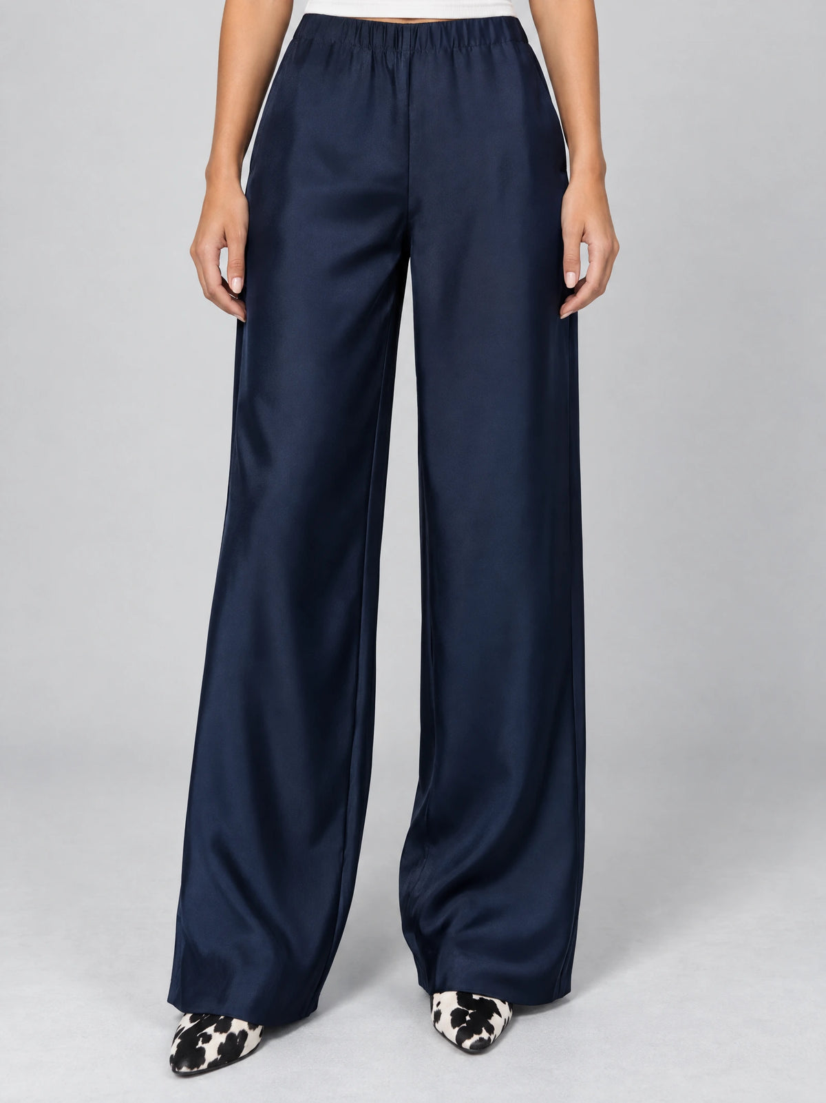 Front studio view of a model wearing Navy satin wide leg pants with a high elastic waist.