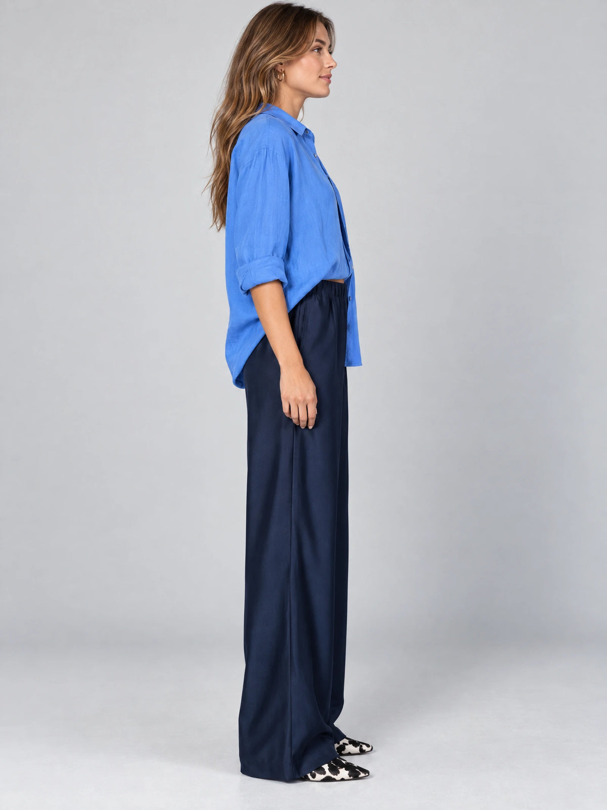 Side studio view of a model wearing Navy satin wide leg pants with a high elastic waist.