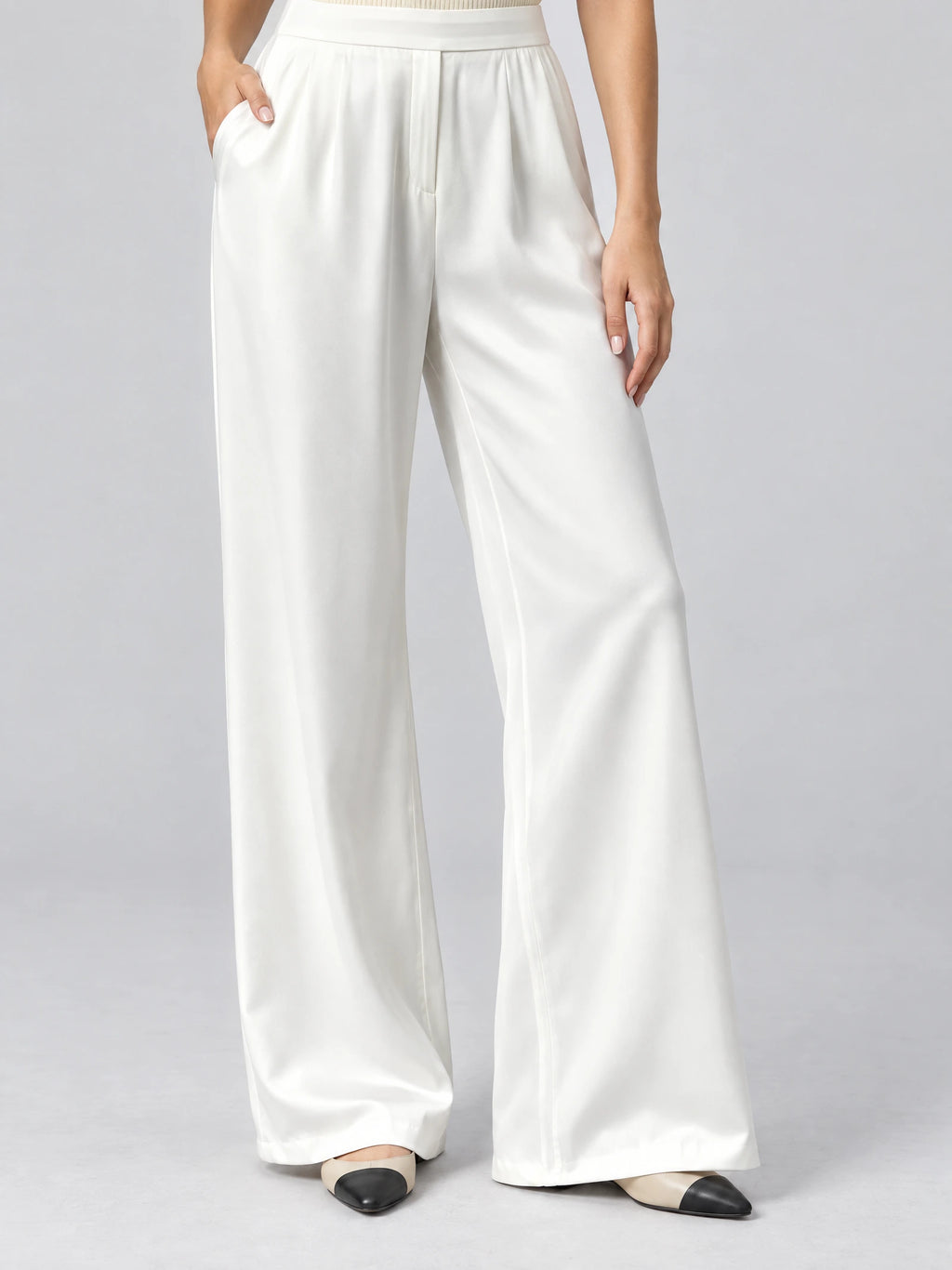 Front studio view of a model wearing White satin wide leg pants with a high waistband and side pockets.