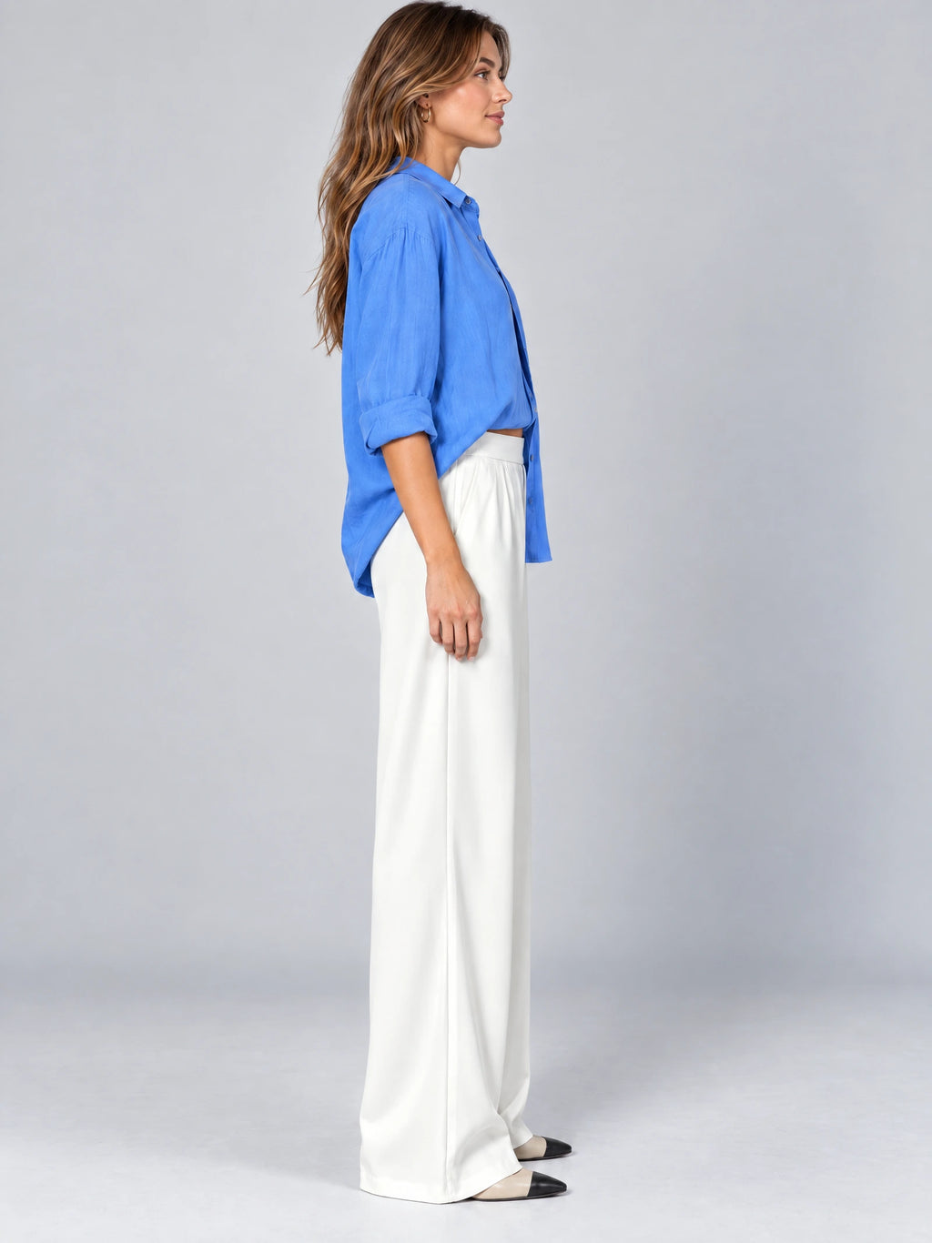 Side studio view of a model wearing White satin wide leg pants with a high waist and flowing full-length legs.