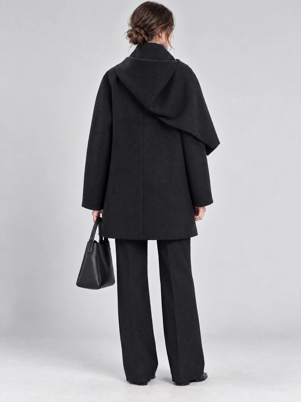 Rear studio view of a model wearing a Black scarf collar wool coat with a draped back collar.