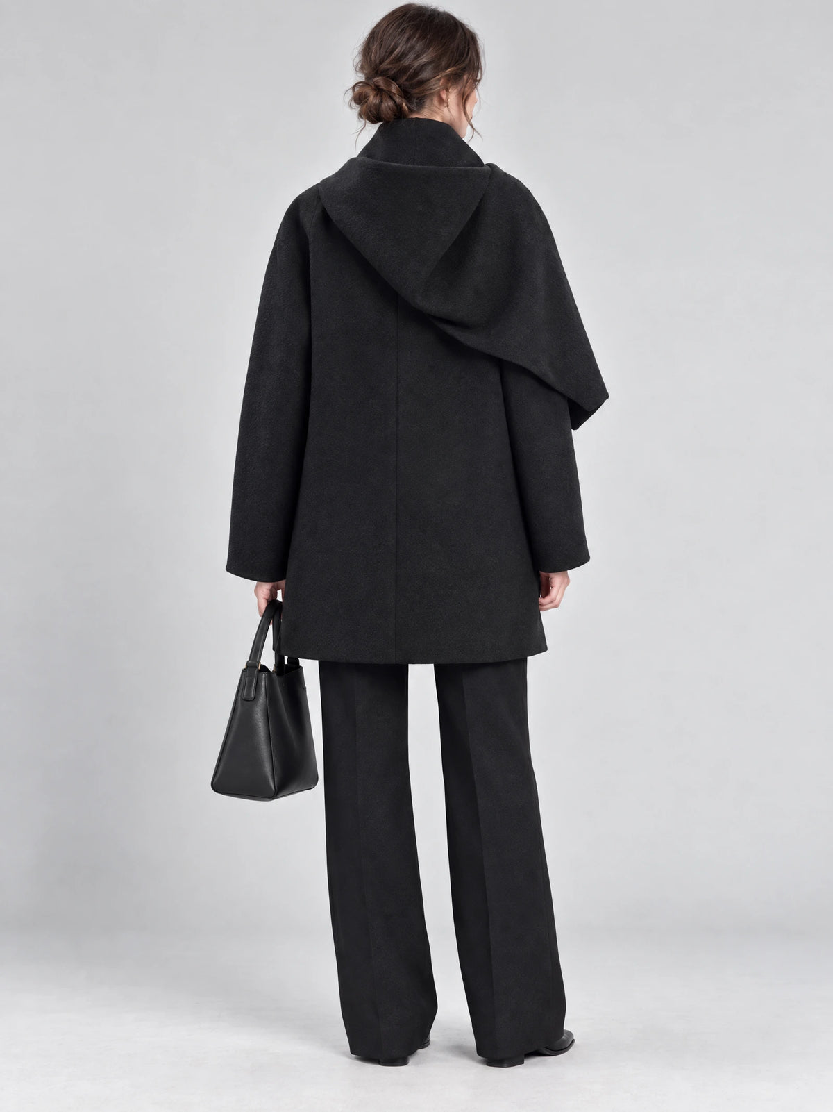 Rear studio view of a model wearing a Black scarf collar wool coat with a draped back collar.