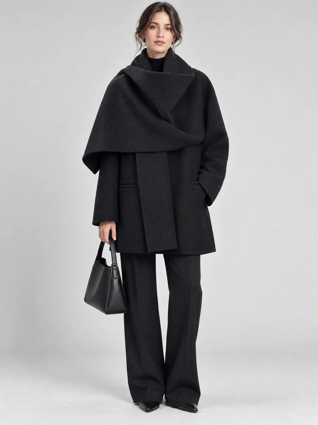 Front studio view of a model wearing a Black scarf collar wool coat with an oversized draped collar and side pockets.