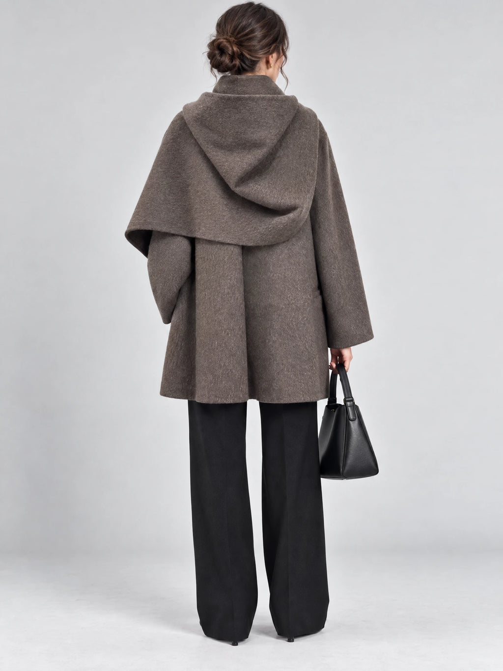 Rear studio view of a model wearing a Brown wool coat with a draped scarf collar and wide sleeves.