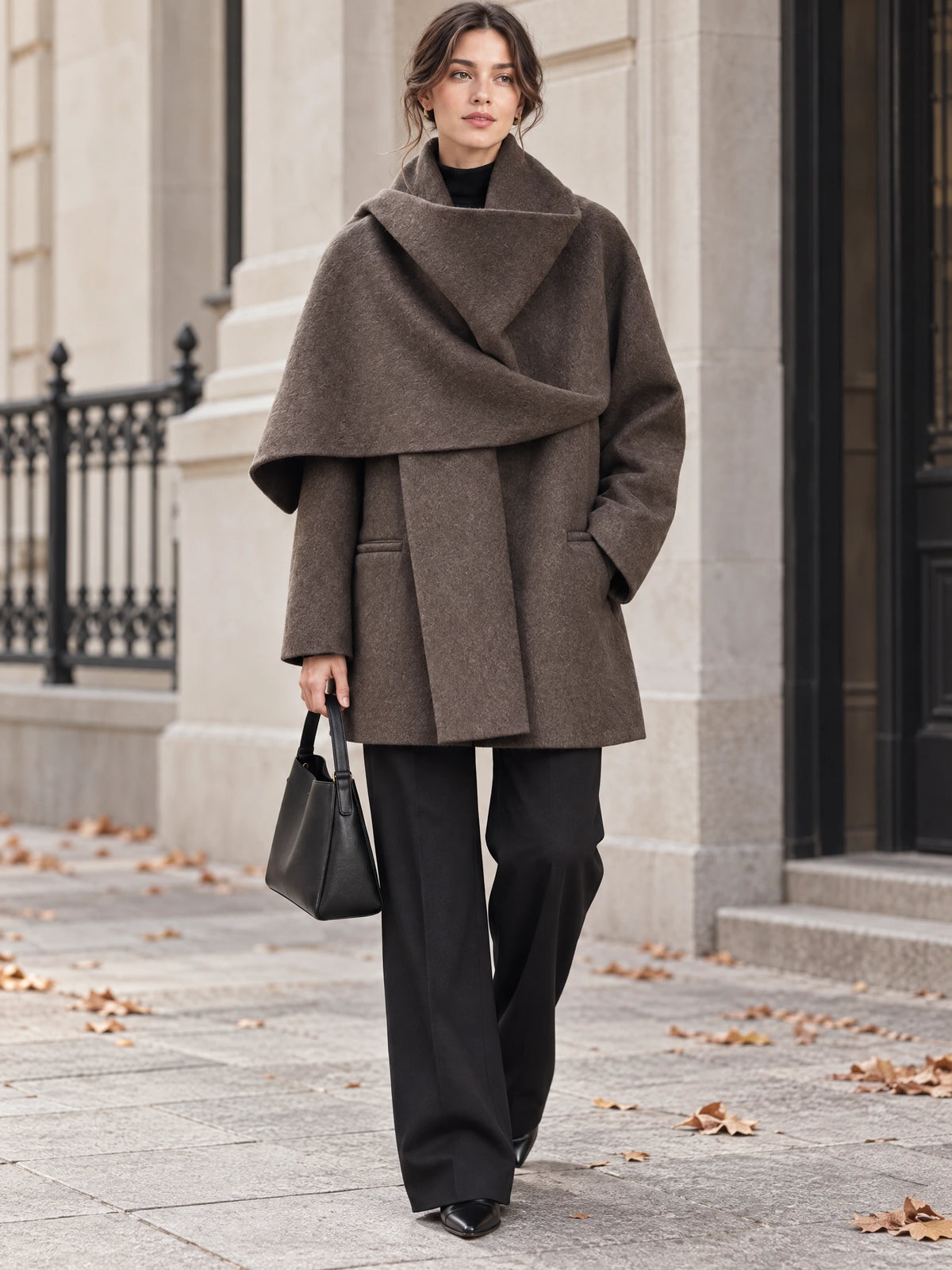 Model walking on a city sidewalk in a Brown wool coat with an oversized scarf collar and front pockets.
