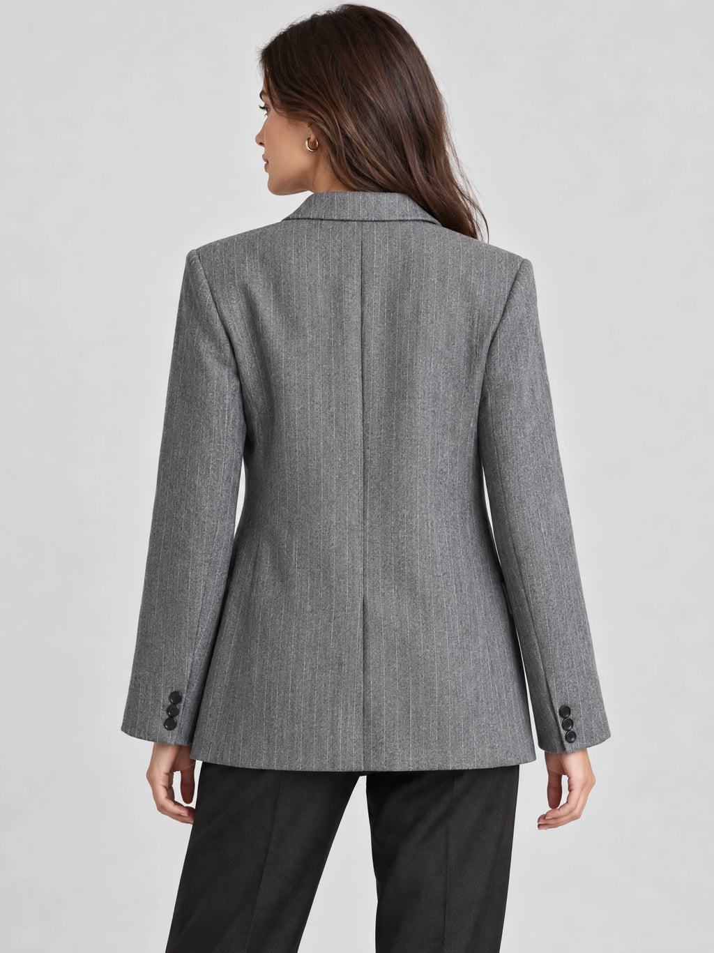 Rear view of a model wearing a Gray striped single breasted blazer with a center back seam and buttoned cuffs.