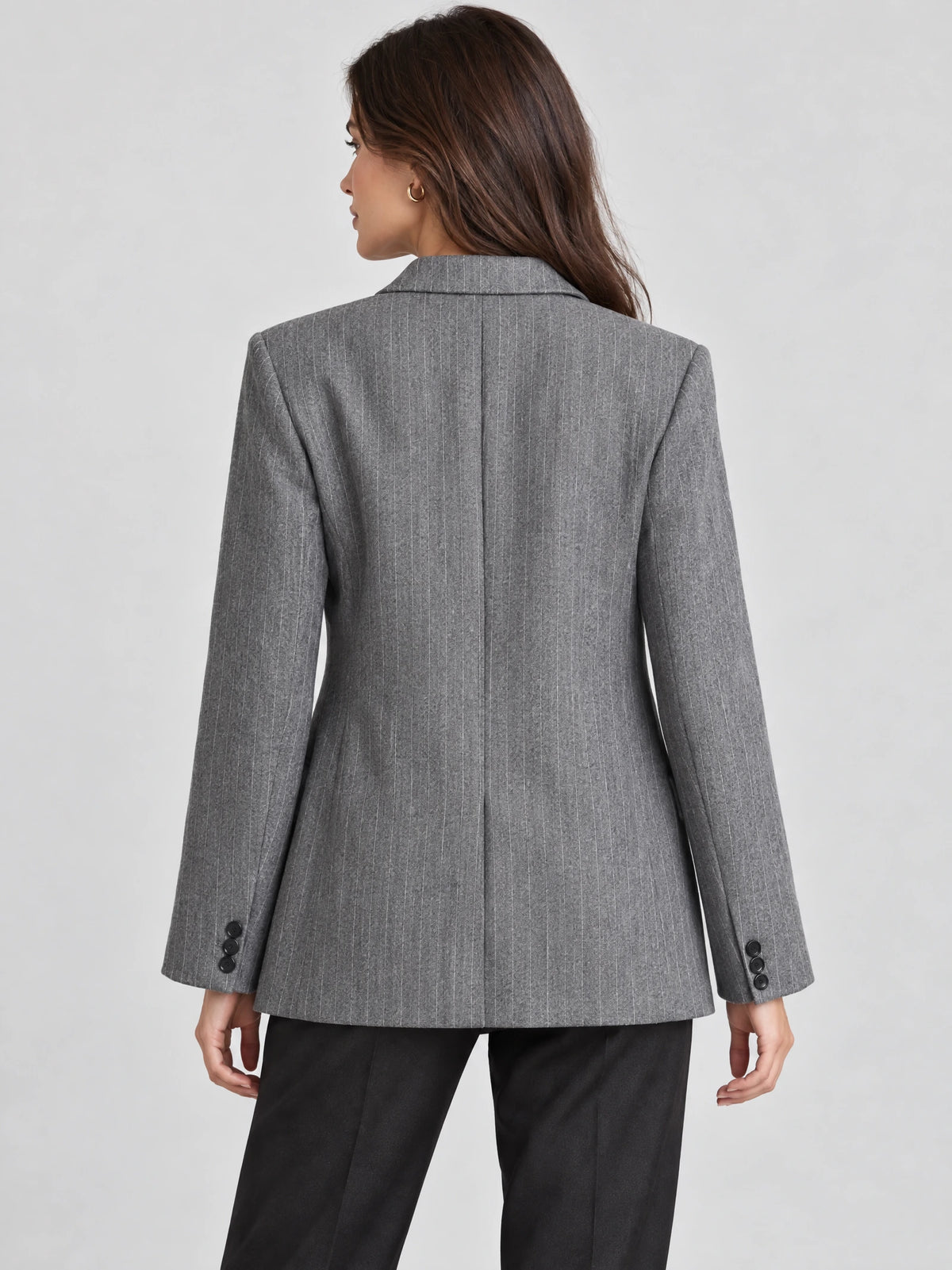 Rear view of a model wearing a Gray striped single breasted blazer with a center back seam and buttoned cuffs.