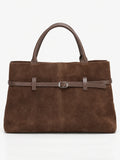 Brown suede leather tote bag in a front studio view with double handles and a buckle-accented strap.