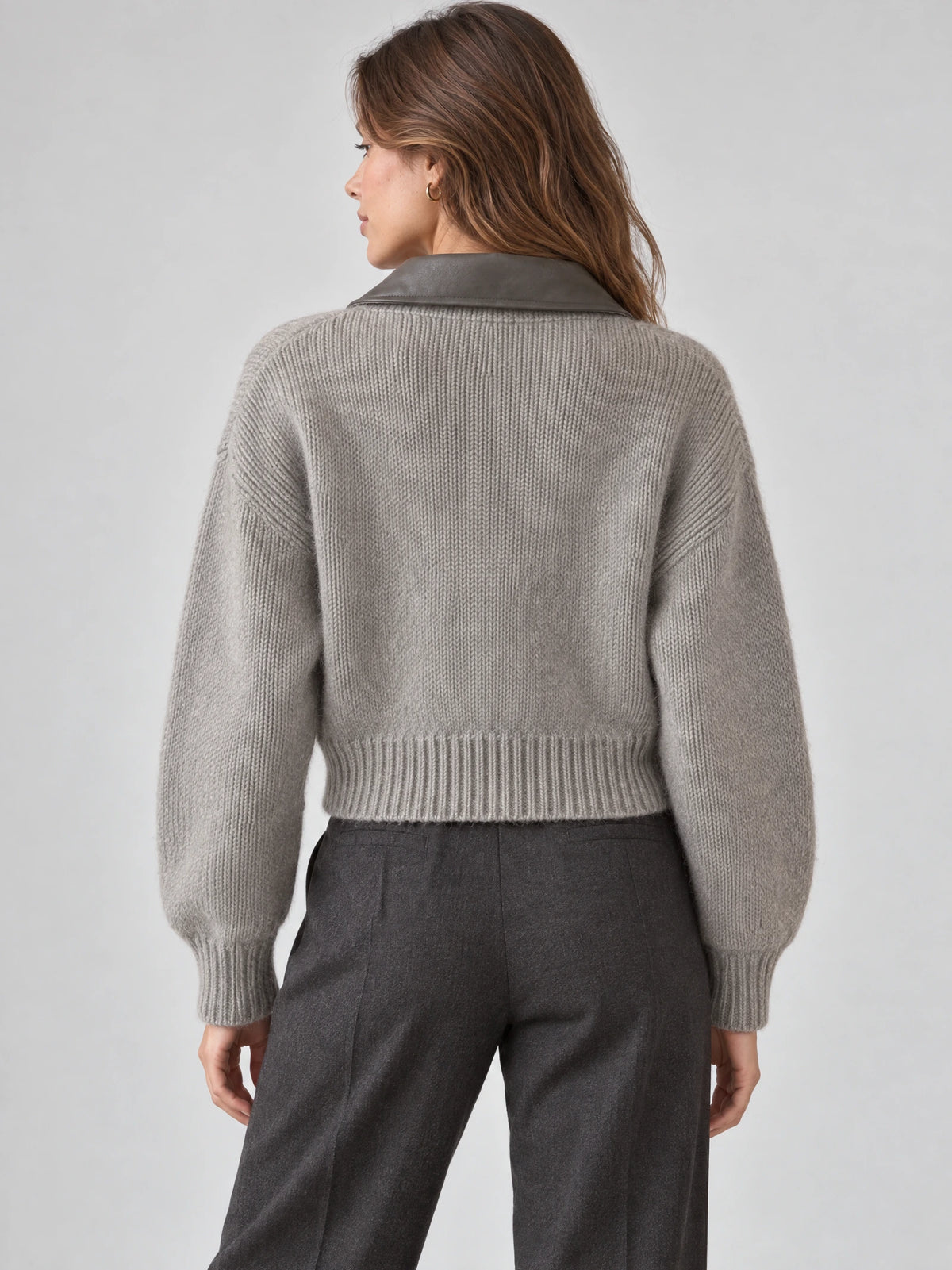 Rear studio view of a model wearing a Gray cropped knit cardigan with a wide lapel, ribbed hem, and cuffs.