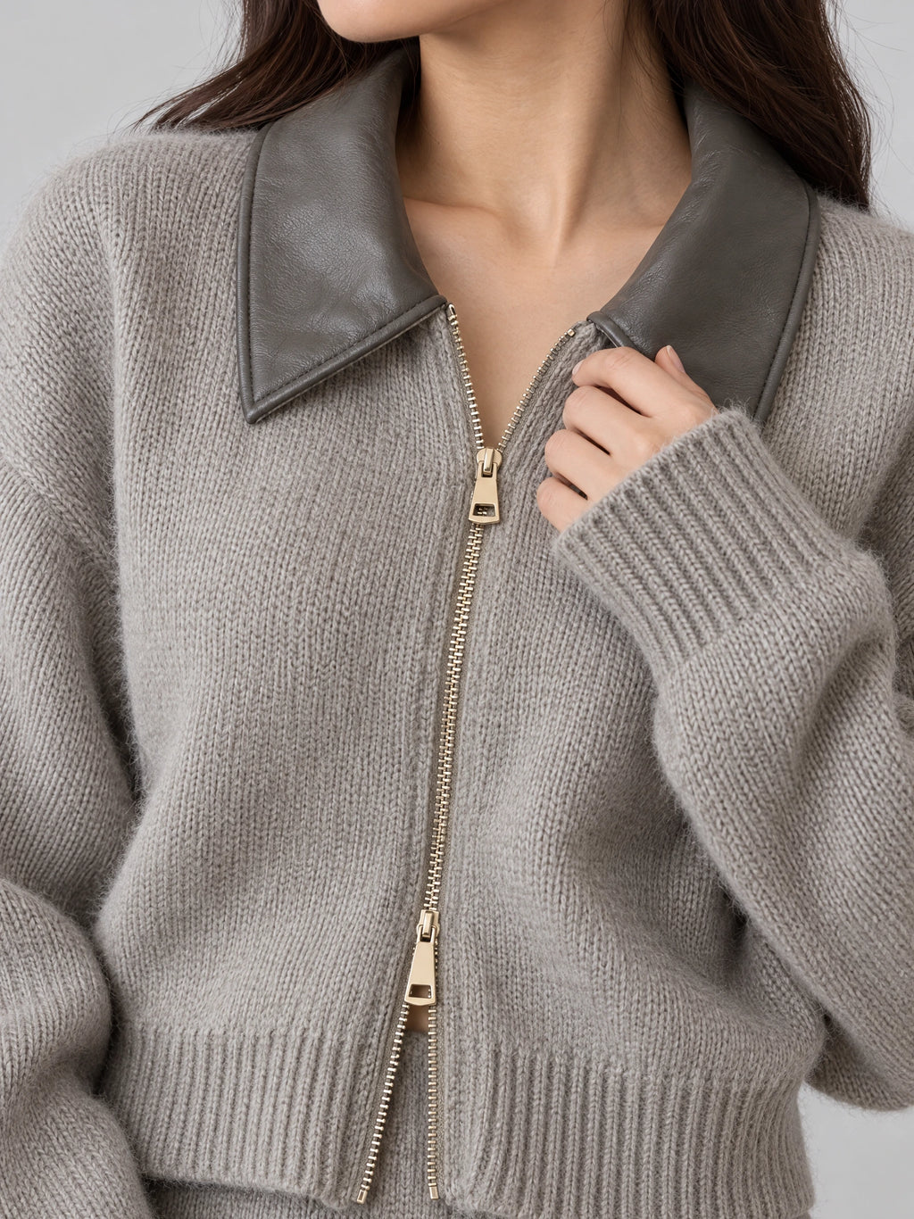 Close-up of a Gray thick knitted cardigan showing the oversized lapel, ribbed cuffs, and two-way front zipper.
