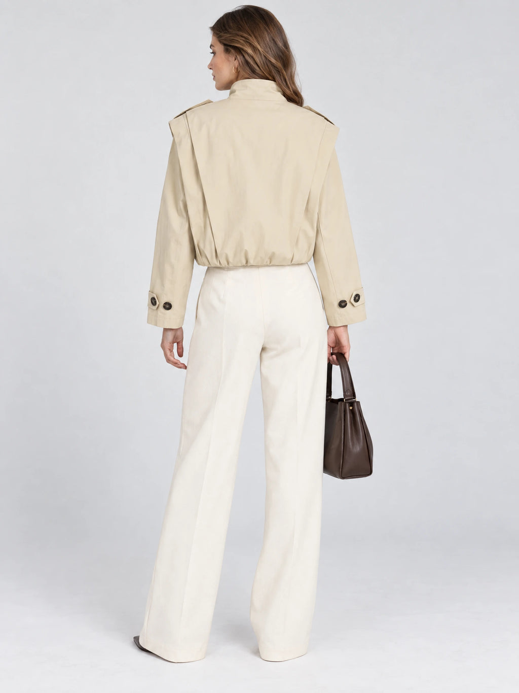 Rear view of a model wearing a Khaki cropped stand-collar trench coat with shoulder tabs and buttoned cuffs.