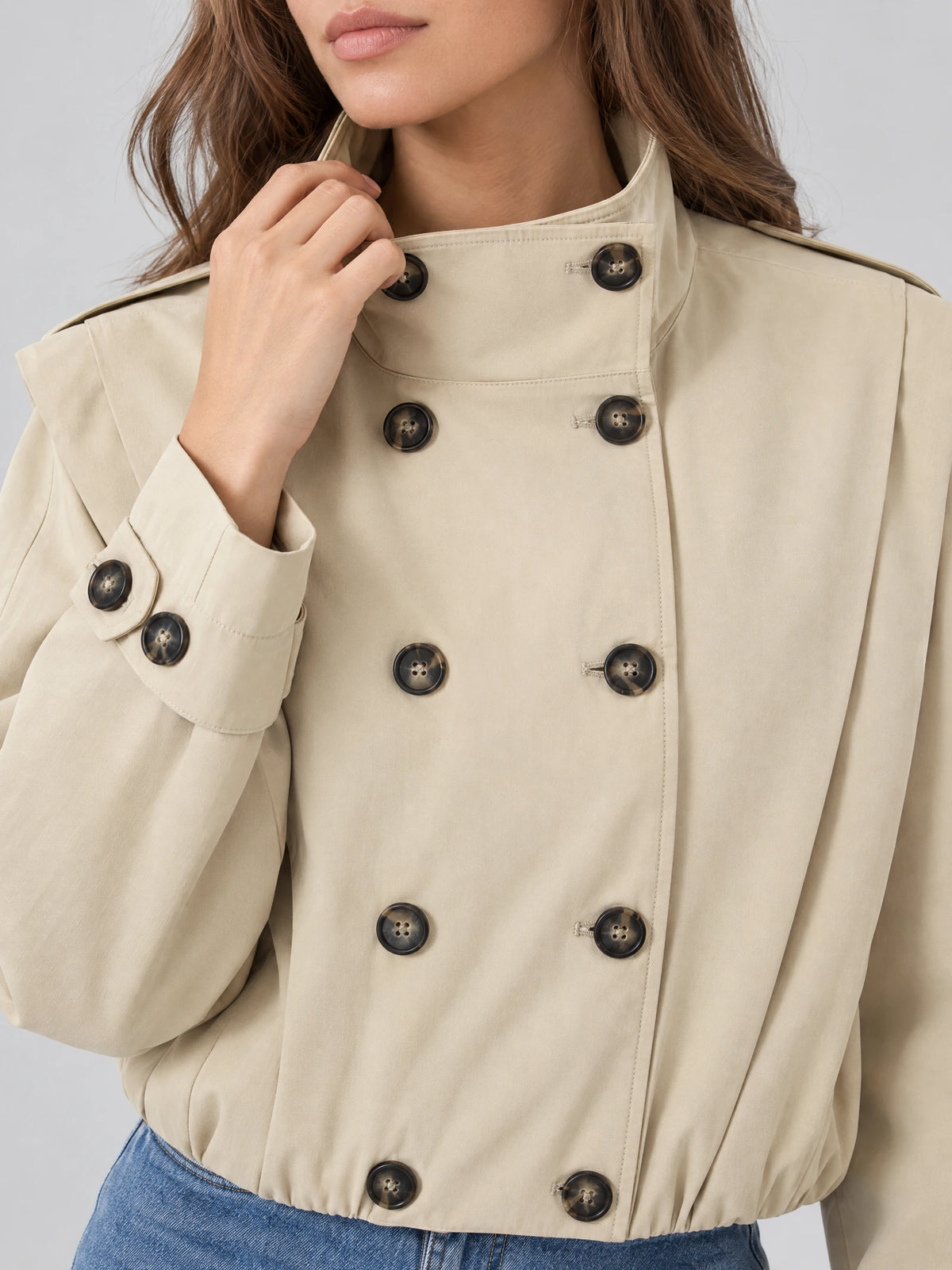 Close-up of a Khaki trench coat stand collar with double-breasted buttons and buttoned cuff detail.