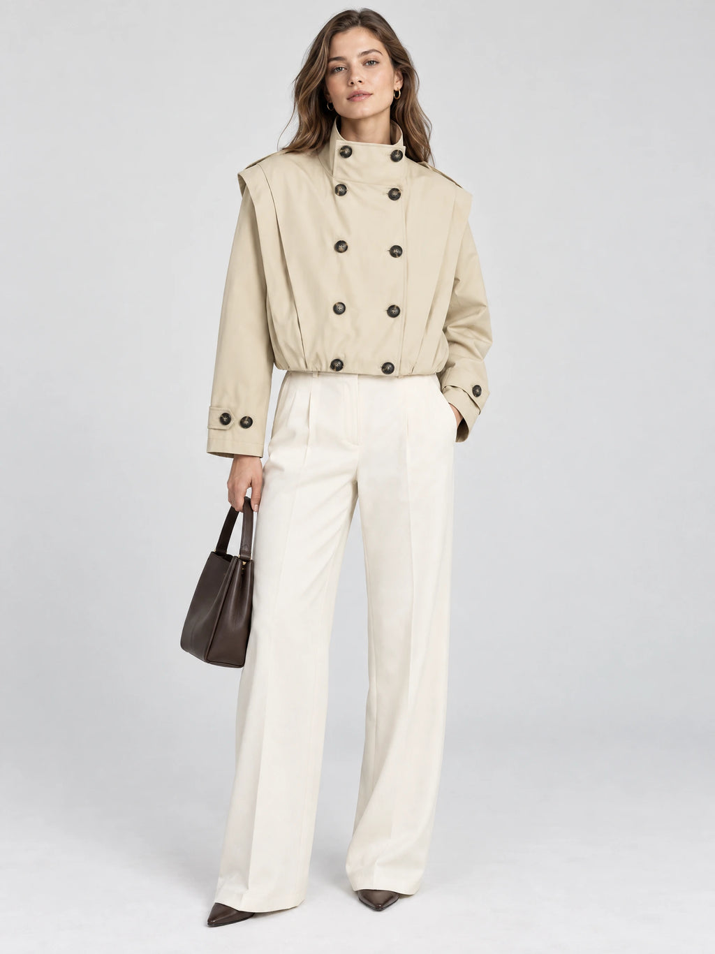 Front studio view of a model wearing a Khaki cropped double-breasted trench coat with a stand collar and buttoned cuffs.