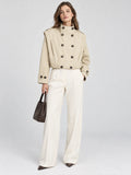 Front studio view of a model wearing a Khaki cropped double-breasted trench coat with a stand collar and buttoned cuffs.