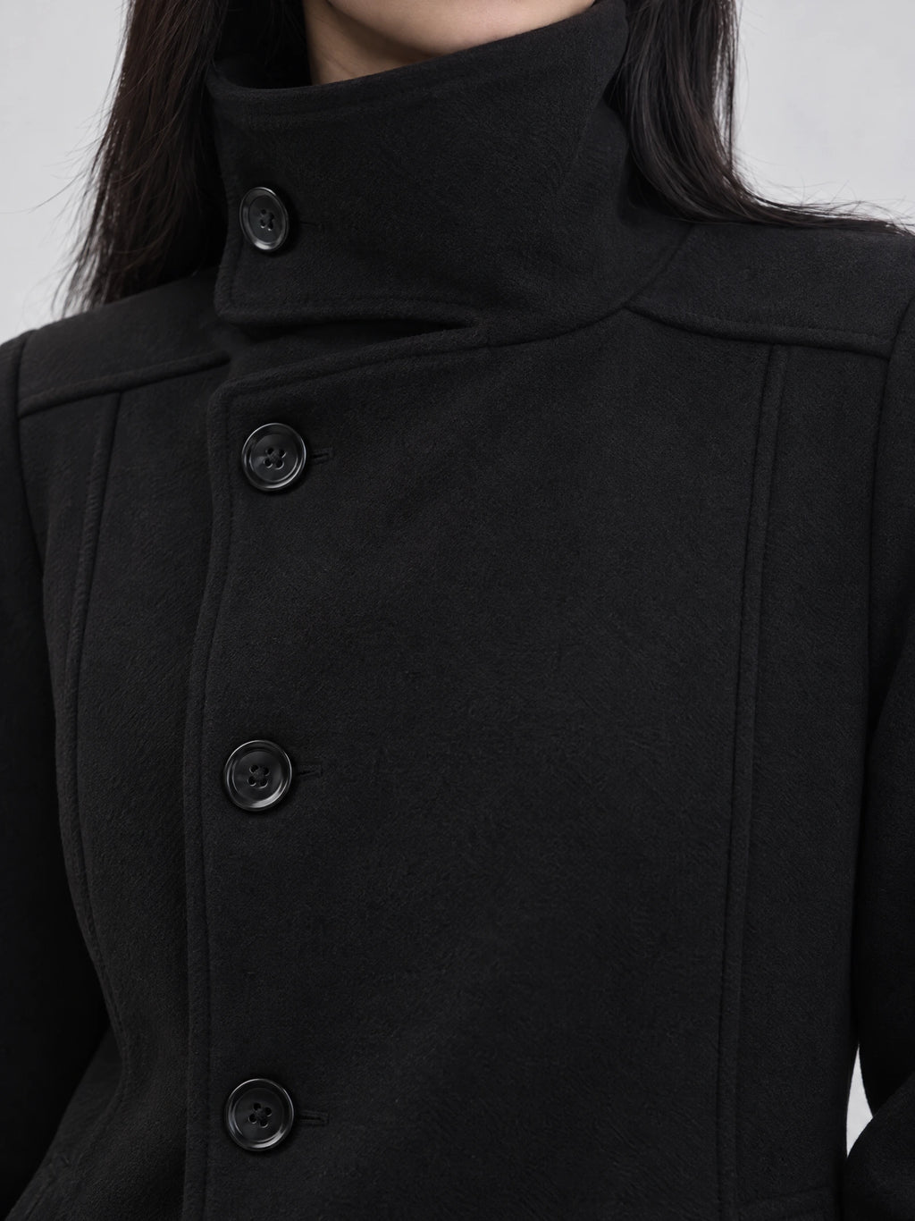 Close-up of the Black womens turtleneck coat showing its high collar, button-front closure, and textured fabric.