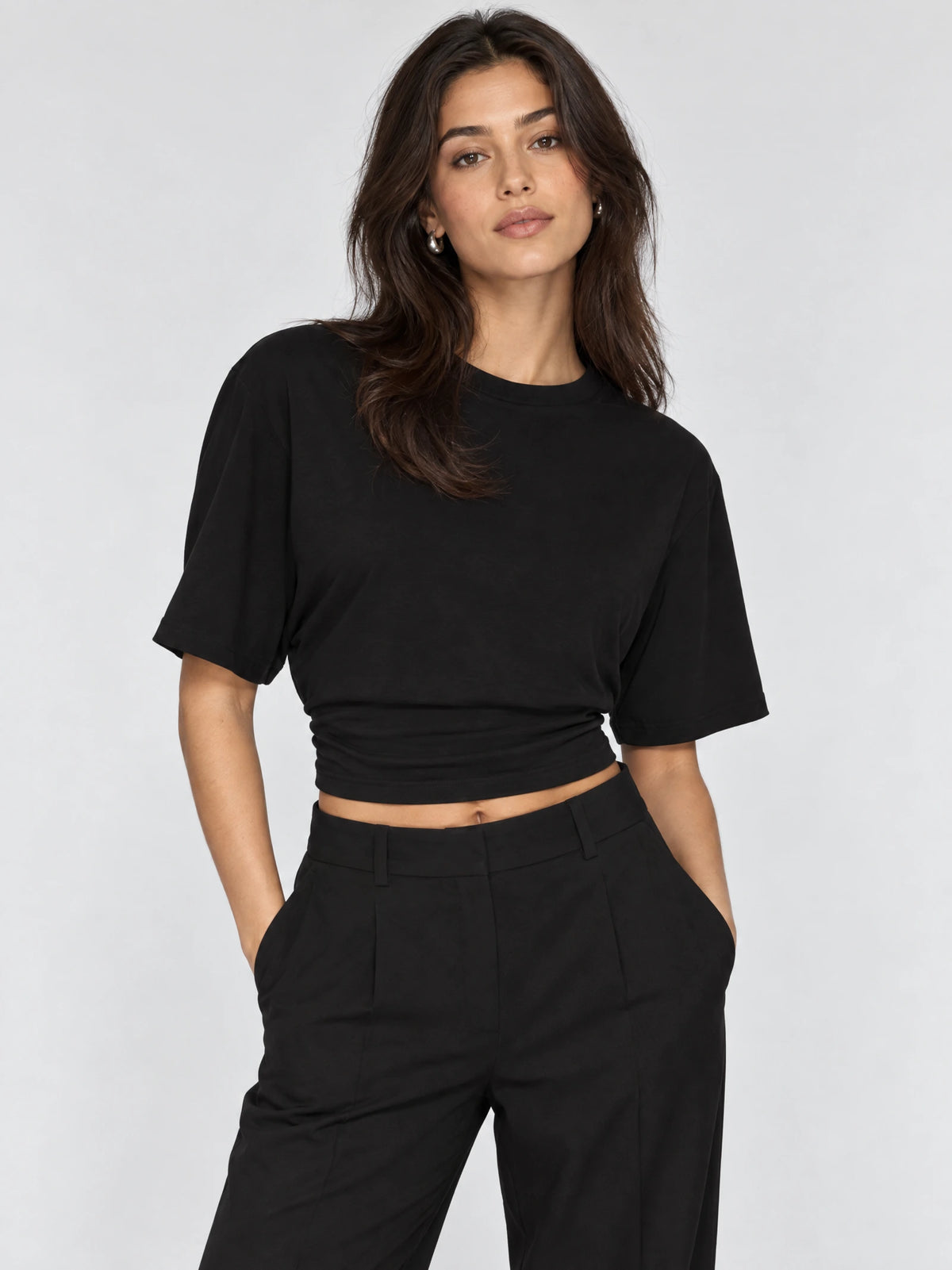 Model wearing a Black waist short top with a round neckline and short sleeves in a front studio view.