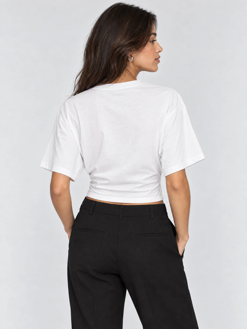 Back view of a model wearing a White cotton waist short top with short sleeves and a fitted hem.