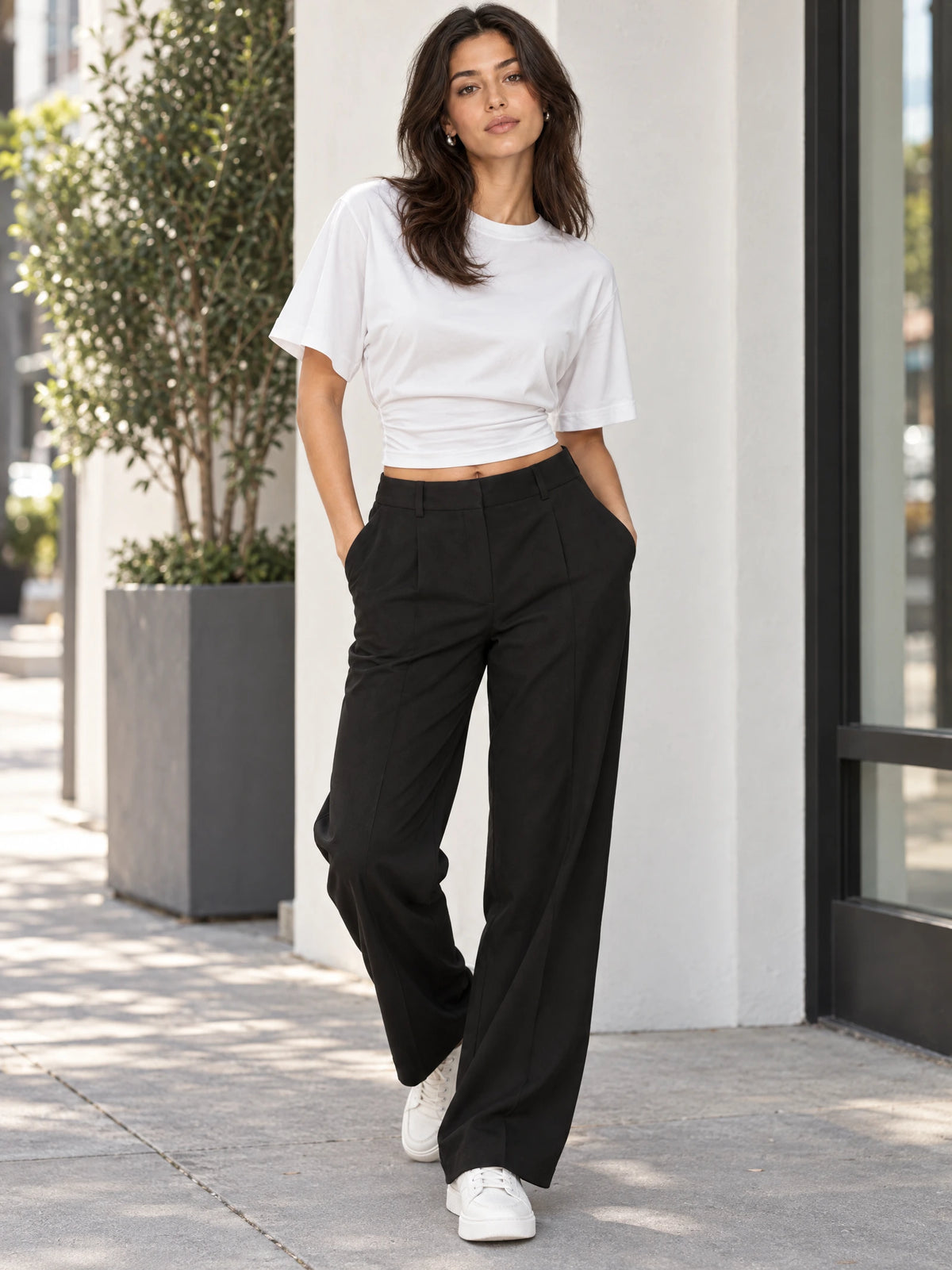 Model wearing a White cotton Waist Short Top with a crew neckline and gathered waist while walking outdoors.
