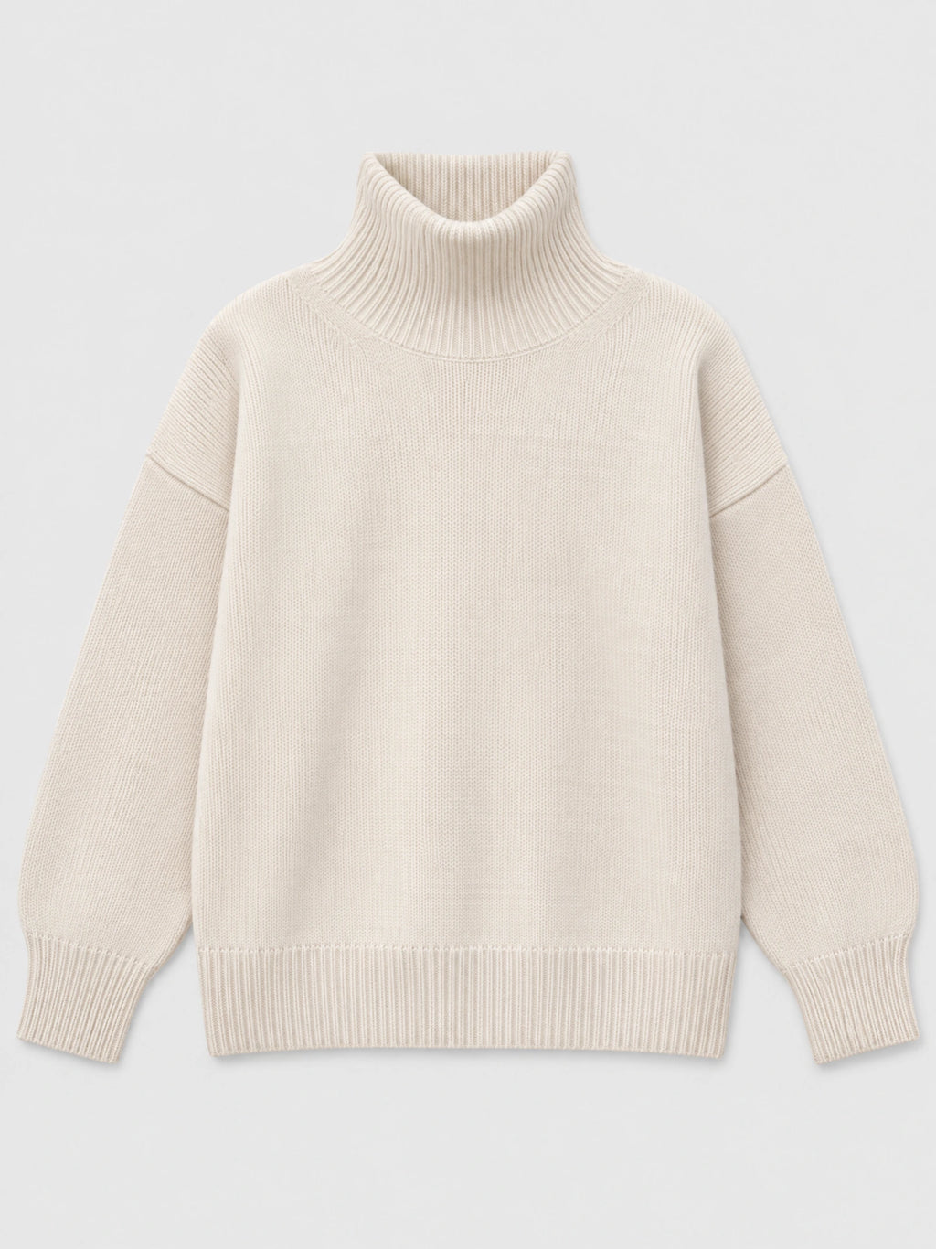 Beige women’s turtleneck sweater laid flat, featuring a ribbed high neck, dropped shoulders, and ribbed cuffs and hem.