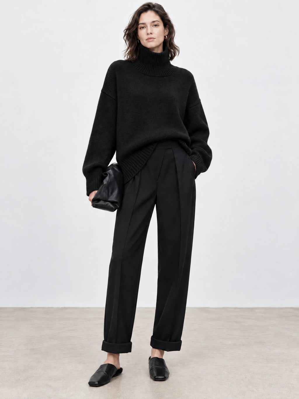 Model wearing a Black wool turtleneck sweater with ribbed collar, cuffs, and hem in a front studio view.