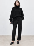 Model wearing a Black wool turtleneck sweater with ribbed collar, cuffs, and hem in a front studio view.