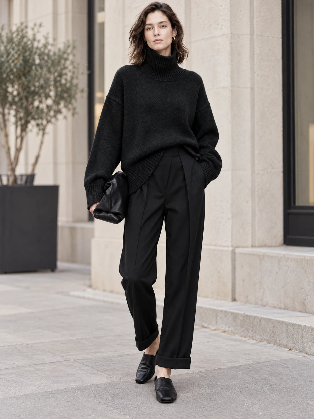 Model wearing a Black wool turtleneck sweater with ribbed collar and cuffs on a city sidewalk.