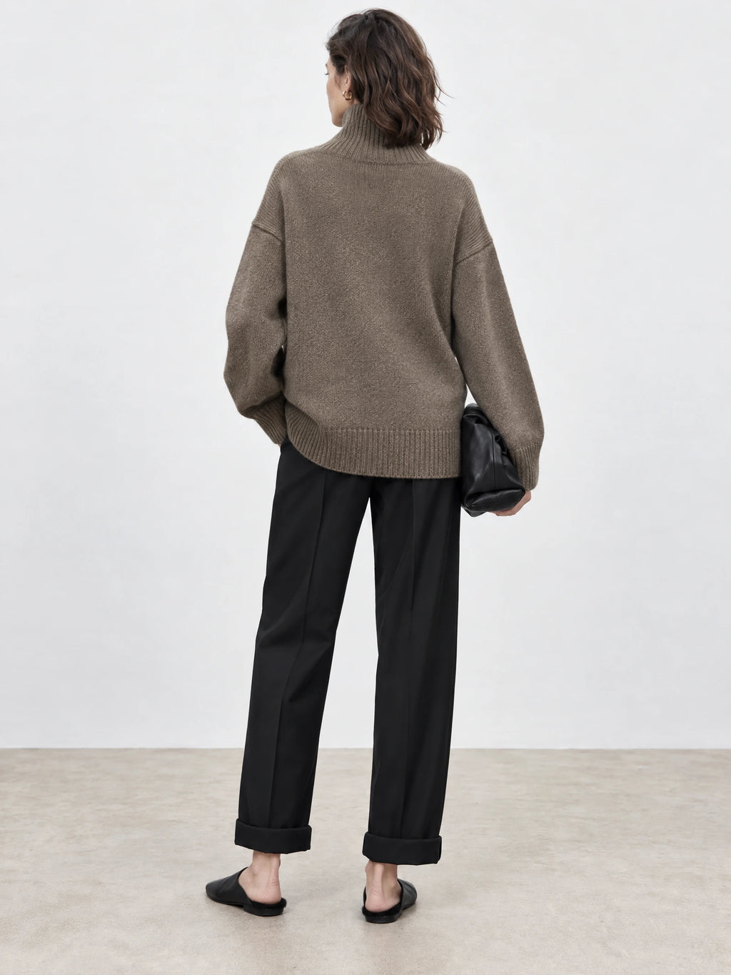 Back view of a model wearing a Brown turtleneck sweater with ribbed collar, cuffs, and hem.