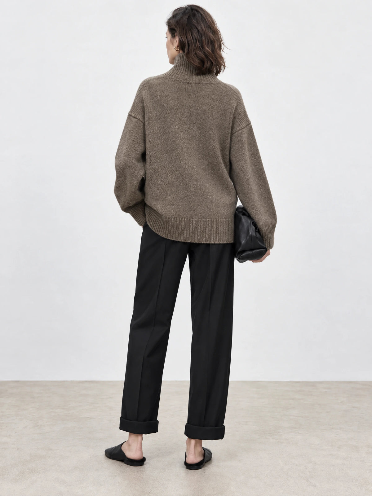 Back view of a model wearing a Brown turtleneck sweater with ribbed collar, cuffs, and hem.