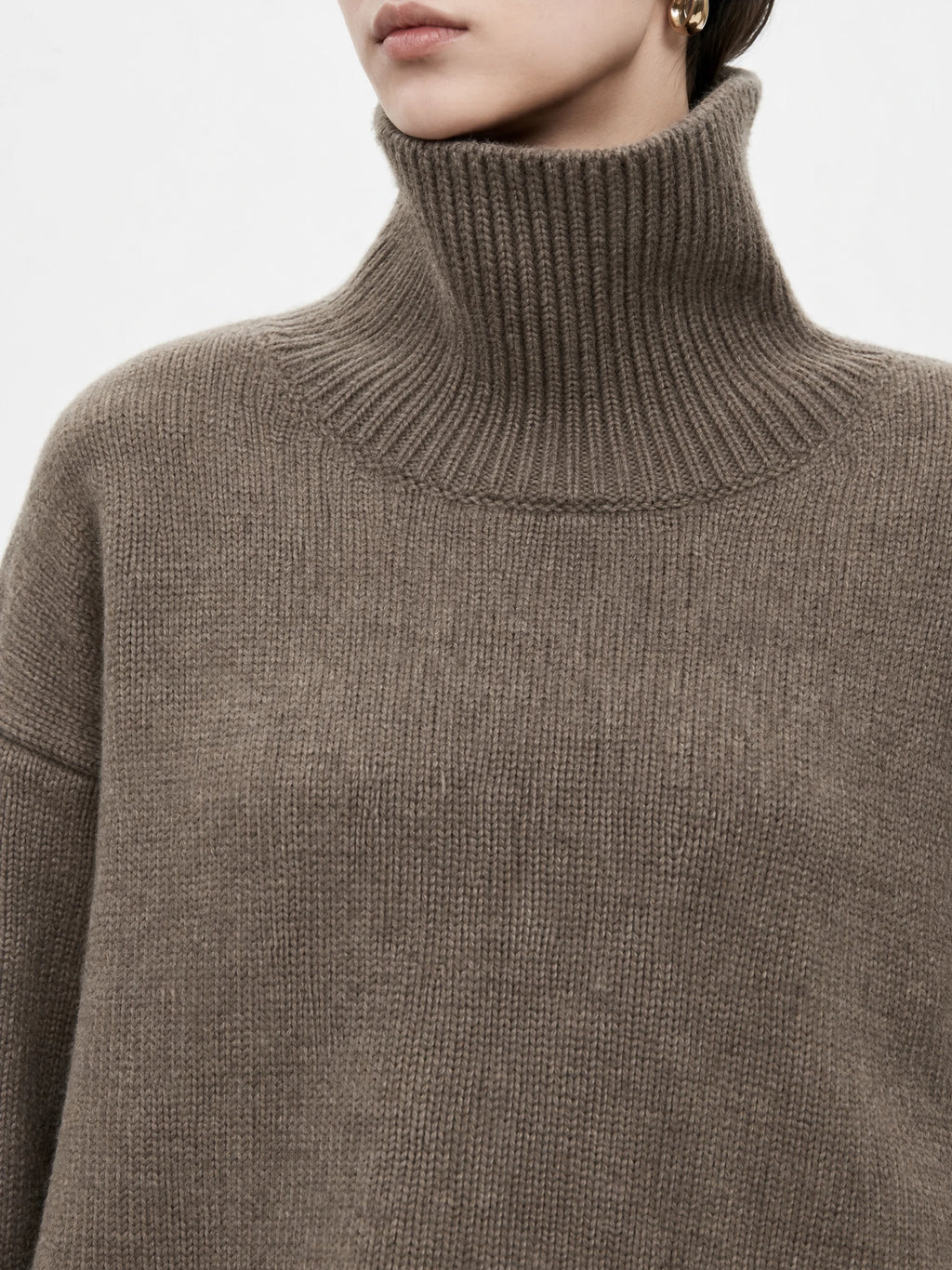 Close-up of the Brown women's turtleneck sweater, highlighting its ribbed high collar and knit texture.