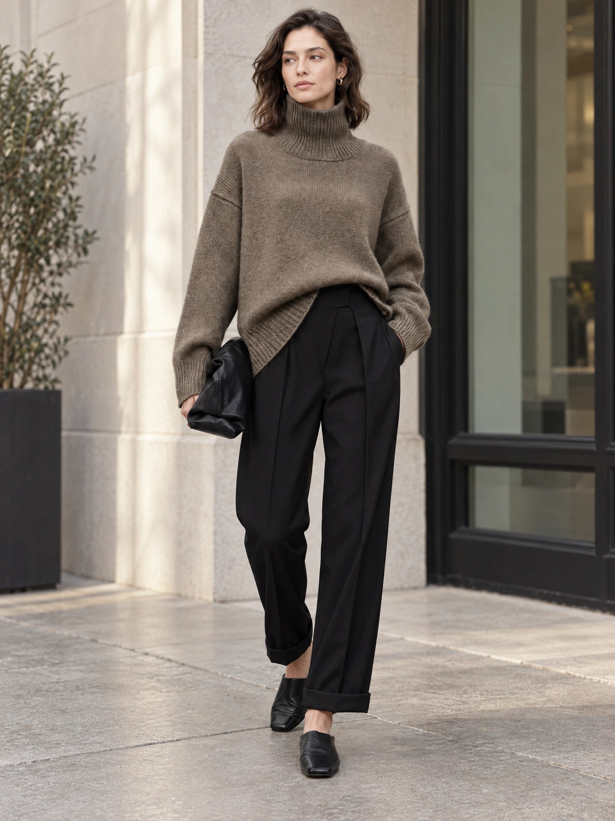 Model walking outside in a Brown wool turtleneck sweater with a ribbed collar, cuffs, and hem.