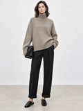 Front studio view of a model wearing a Khaki women's turtleneck sweater with ribbed collar, cuffs, and hem.