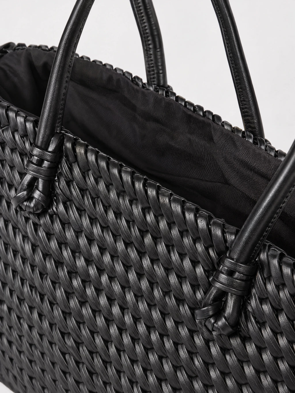 Close-up of the Black woven shoulder bag showing its textured weave, stitched handles, and fabric-lined interior.
