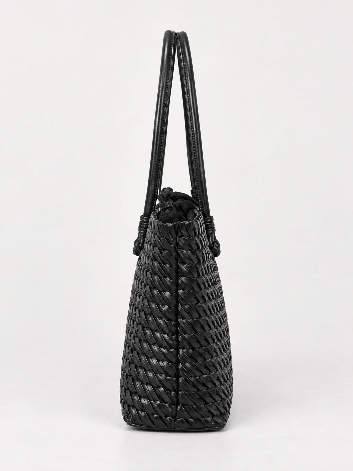 Black woven shoulder bag shown from the side, with a textured woven body, drawstring top, and long double handles.