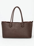 Brown woven shoulder bag with braided texture, knotted handles, and a gathered fabric lining in a front studio view.